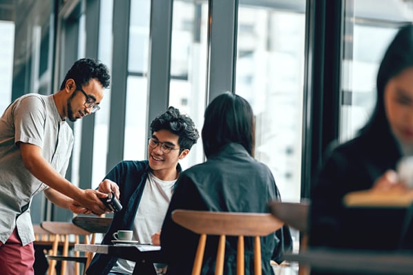 Two customers talking to an employee at a local business joining the loyalty program 