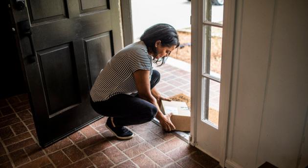 customer benefitting from supply chain visibility by picking up a package at her doorstep that was delivered on time